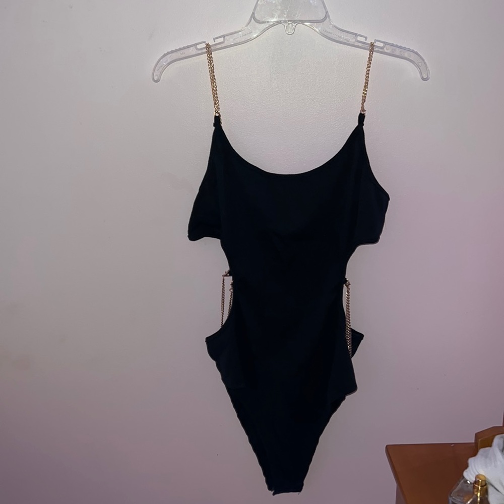 Black body suit with gold shoulder straps